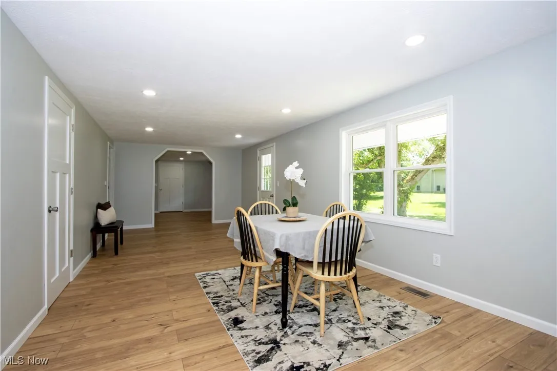 Dining area with arched walkways, recessed lighting, and light wood-style flooring