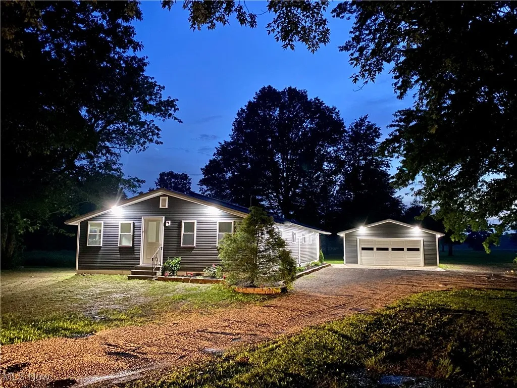 Ranch-style house featuring a garage, an outbuilding, and a front yard