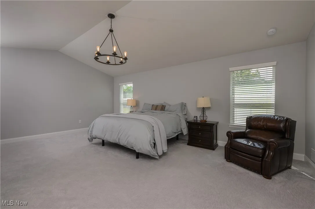 Bedroom with a chandelier, lofted ceiling, and carpet flooring