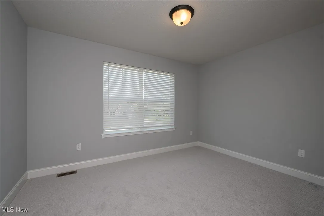 Carpeted spare room featuring baseboards
