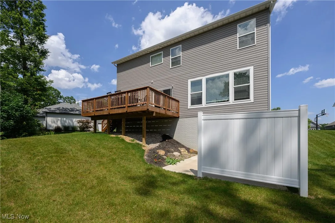 Back of property with a deck and a lawn