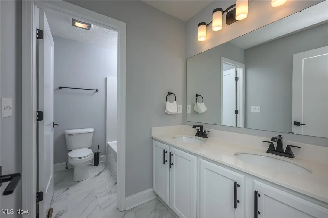 Bathroom with marble look tile flooring and double vanity