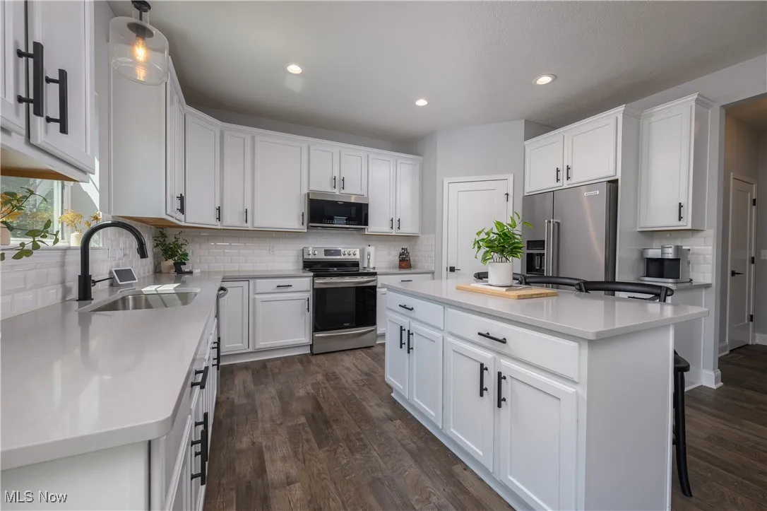 Kitchen with stainless steel appliances, decorative backsplash, white cabinetry, a kitchen island, and recessed lighting