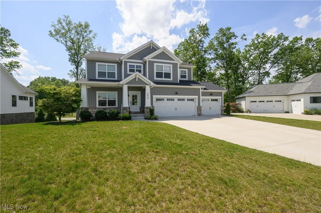 Craftsman inspired home featuring driveway, stone siding, board and batten siding, and a front yard