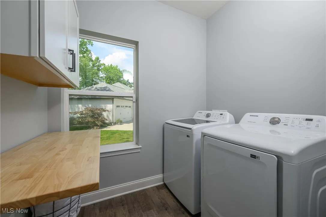 Washroom featuring cabinet space, washing machine and dryer, and dark wood-style floors