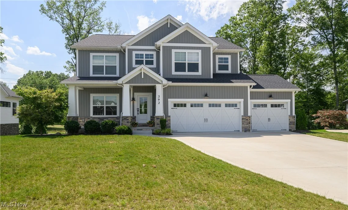 Craftsman house featuring driveway, a front yard, and stone siding