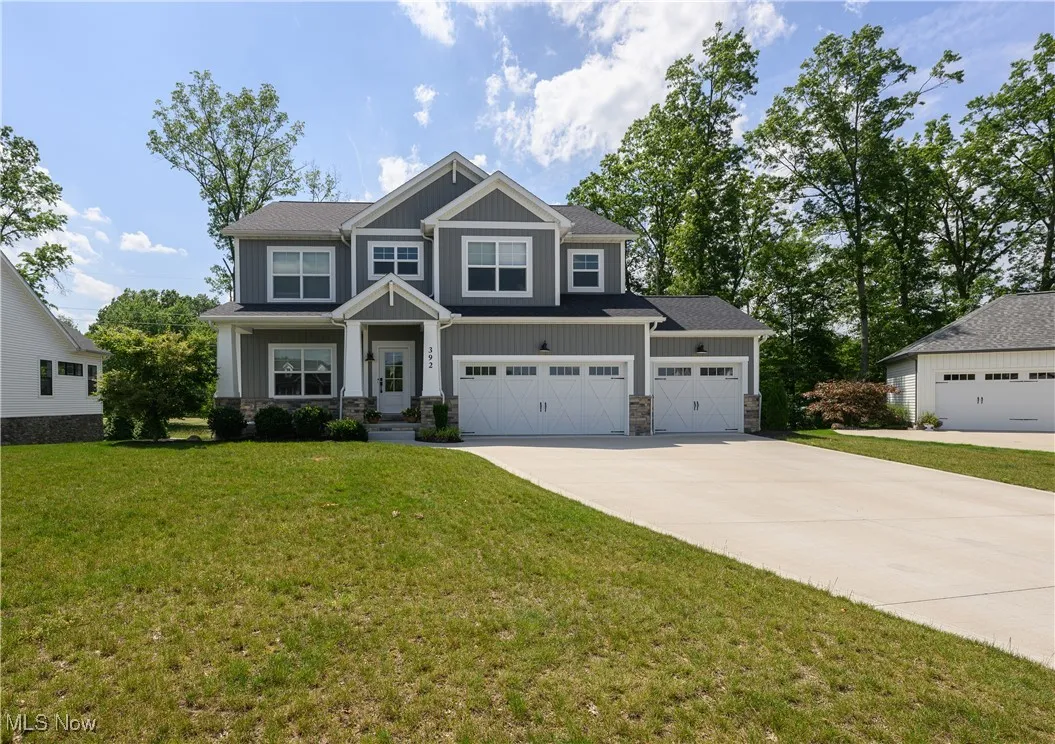 Craftsman inspired home with driveway, stone siding, board and batten siding, and a front lawn