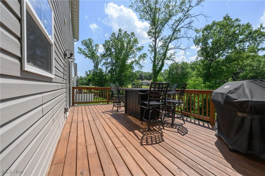 Deck featuring outdoor dining area, area for grilling, and view of scattered trees
