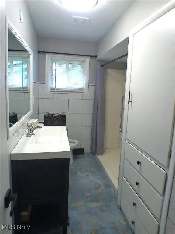 Full bathroom with vanity, curtained shower, and tile walls
