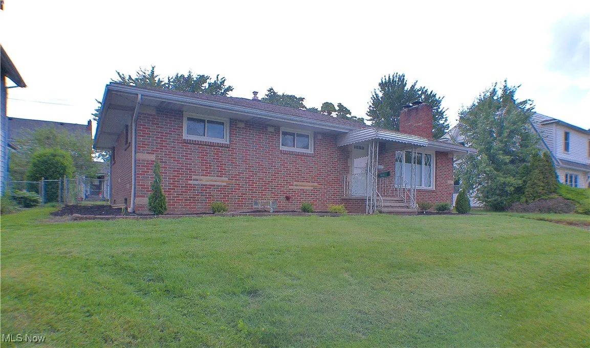 View of front of house featuring brick siding and a chimney