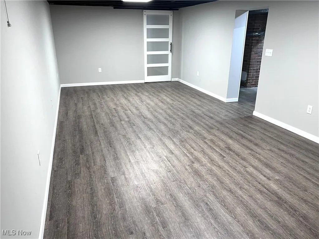 Finished basement with dark wood-type flooring and baseboards