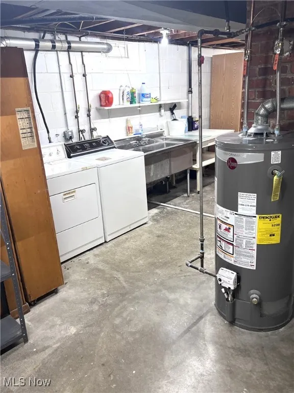 Unfinished basement featuring gas water heater, washing machine and dryer, and concrete block wall