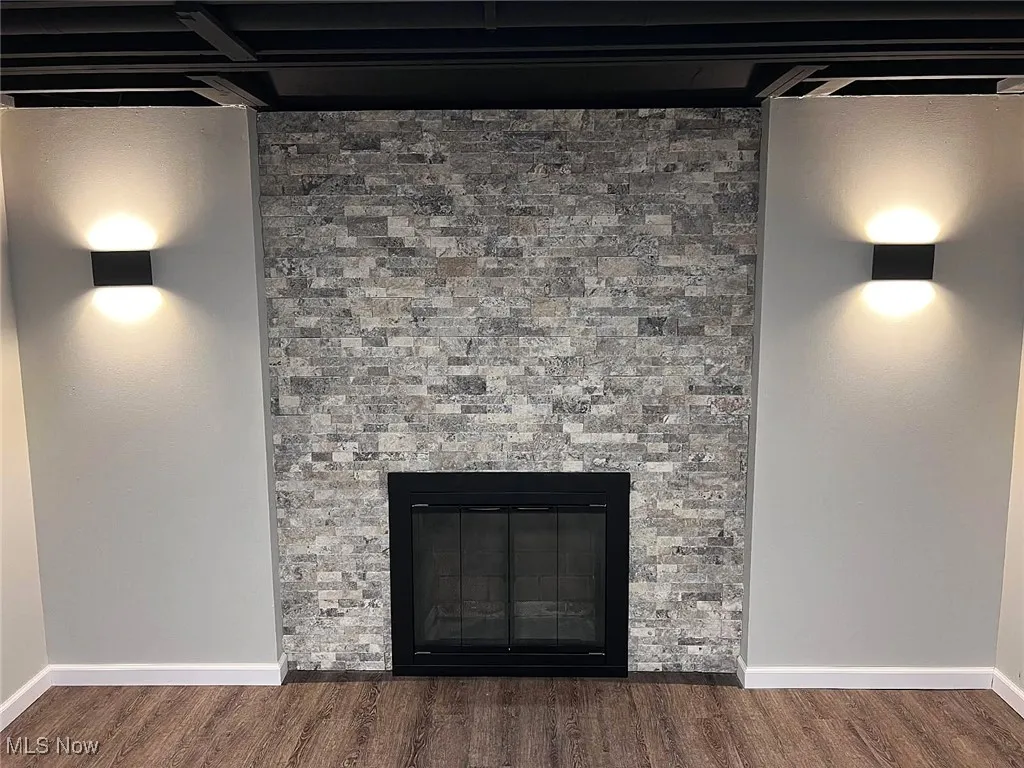 Detailed view of wood finished floors and a stone wood burning fireplace