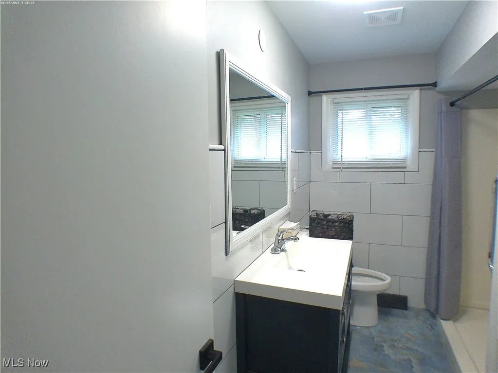 Full bathroom featuring vanity, tile walls, and a shower