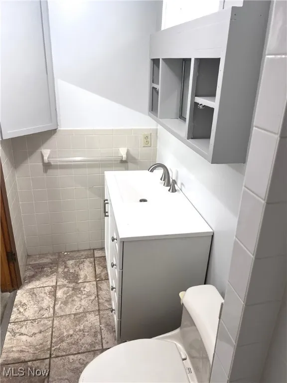 Bathroom with vanity, stone finish flooring, and tile walls