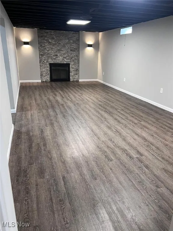 Finished basement with wood finished floors and a stone wood burning fireplace