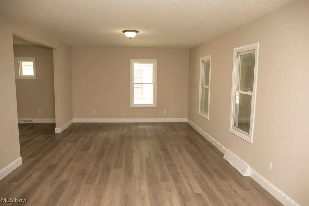 Empty room featuring dark wood-type flooring and a textured ceiling