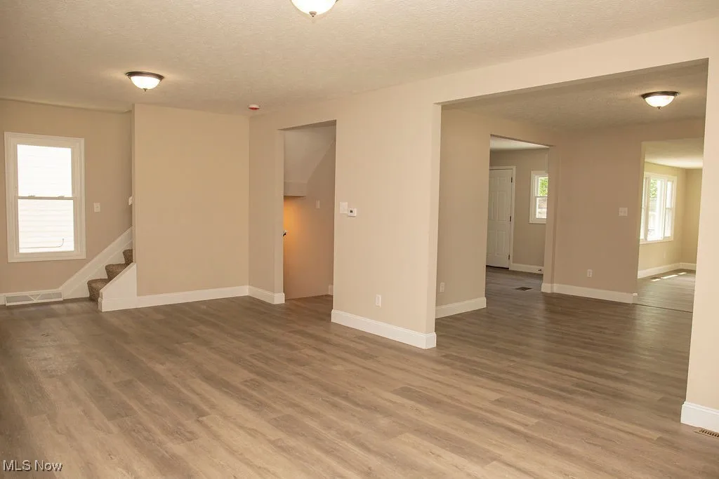 Empty room with wood finished floors, a textured ceiling, and stairs