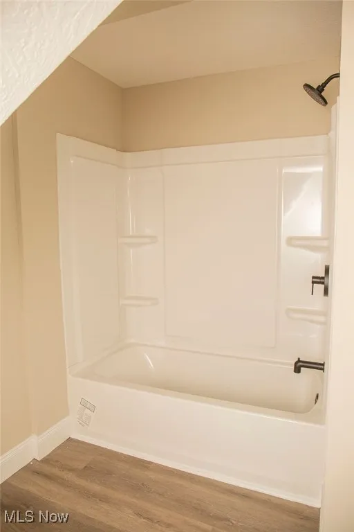 Bathroom with wood finished floors and shower / bathtub combination