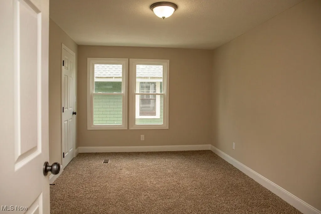 Carpeted empty room with baseboards