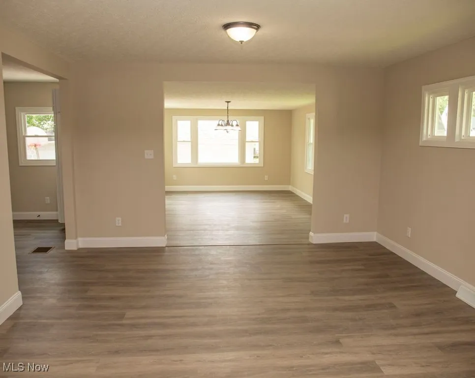Living room featuring a chandelier, healthy amount of natural light, and dark wood finished floors