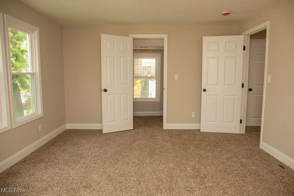 Unfurnished bedroom featuring carpet flooring and multiple windows