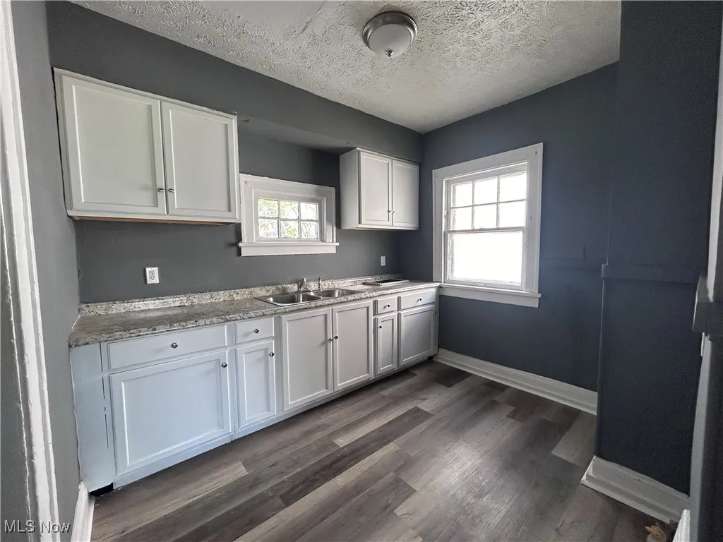Kitchen with white cabinetry, a textured ceiling, and dark wood-type flooring