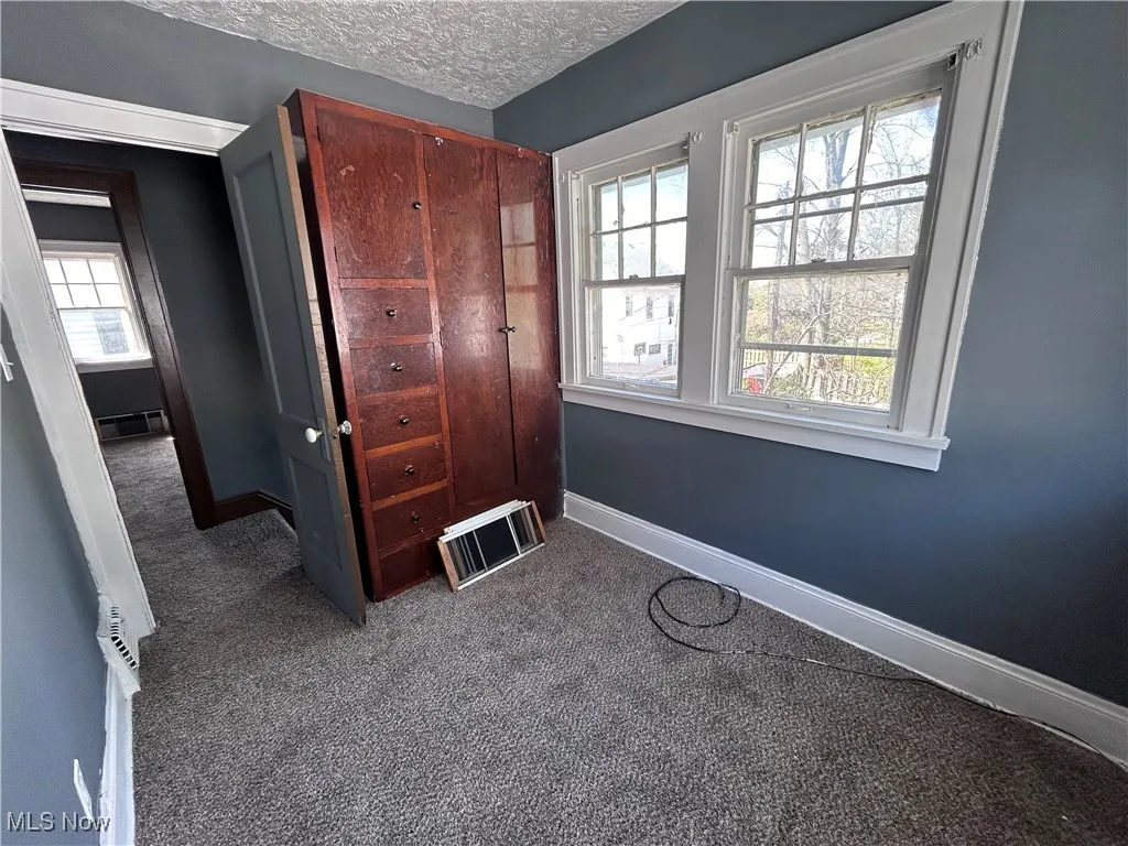 Carpeted bedroom with a textured ceiling and a closet