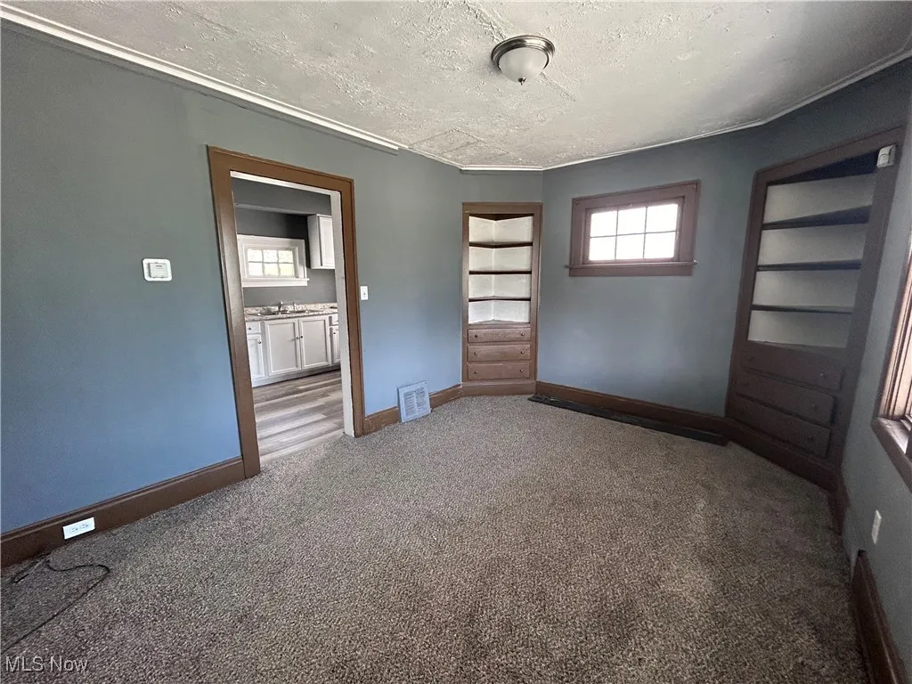 Empty room featuring carpet and a textured ceiling