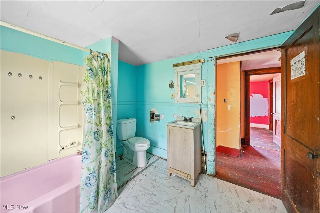Full bathroom featuring shower / tub combo, vanity, and marble look tile flooring