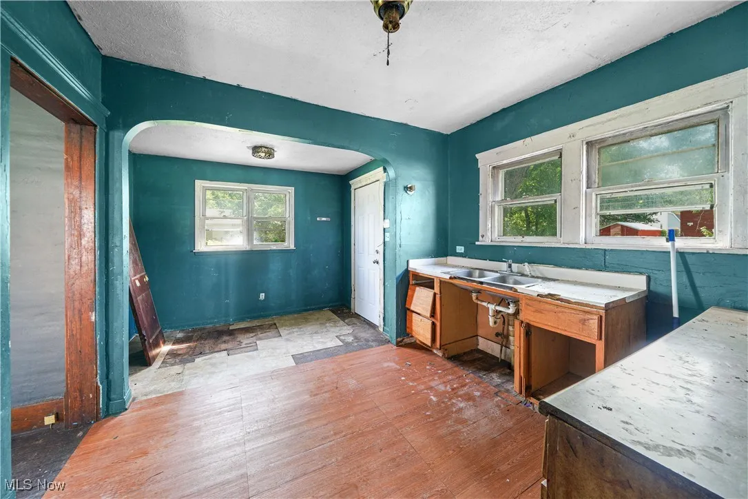 Kitchen with arched walkways, wood finished floors, and a textured ceiling