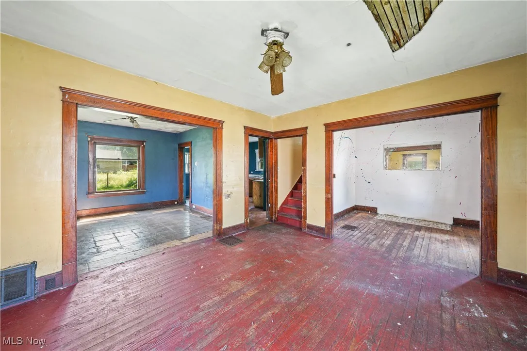 Unfurnished room with stairway, hardwood / wood-style floors, and ceiling fan