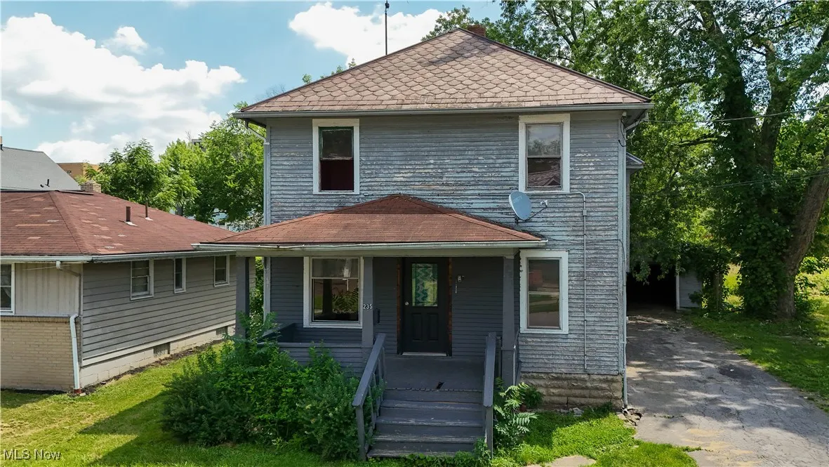 View of front of property with a porch, a shingled roof, and asphalt driveway