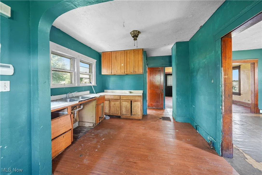 Kitchen with dark wood-style floors, light countertops, arched walkways, and a textured ceiling