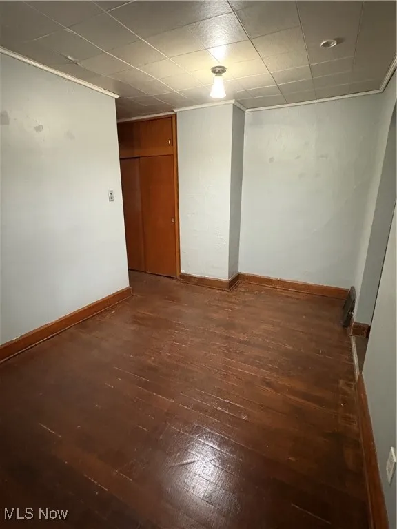 Empty room with dark wood finished floors and crown molding