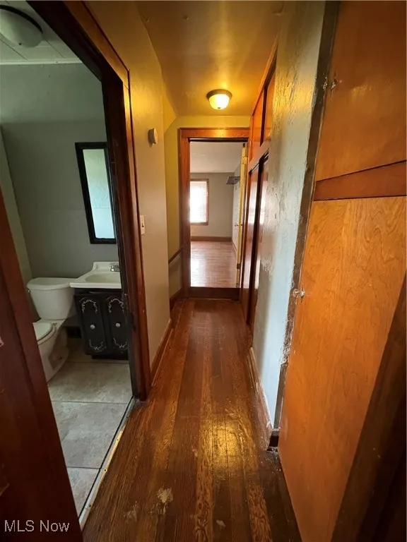Corridor featuring dark wood-type flooring and baseboards