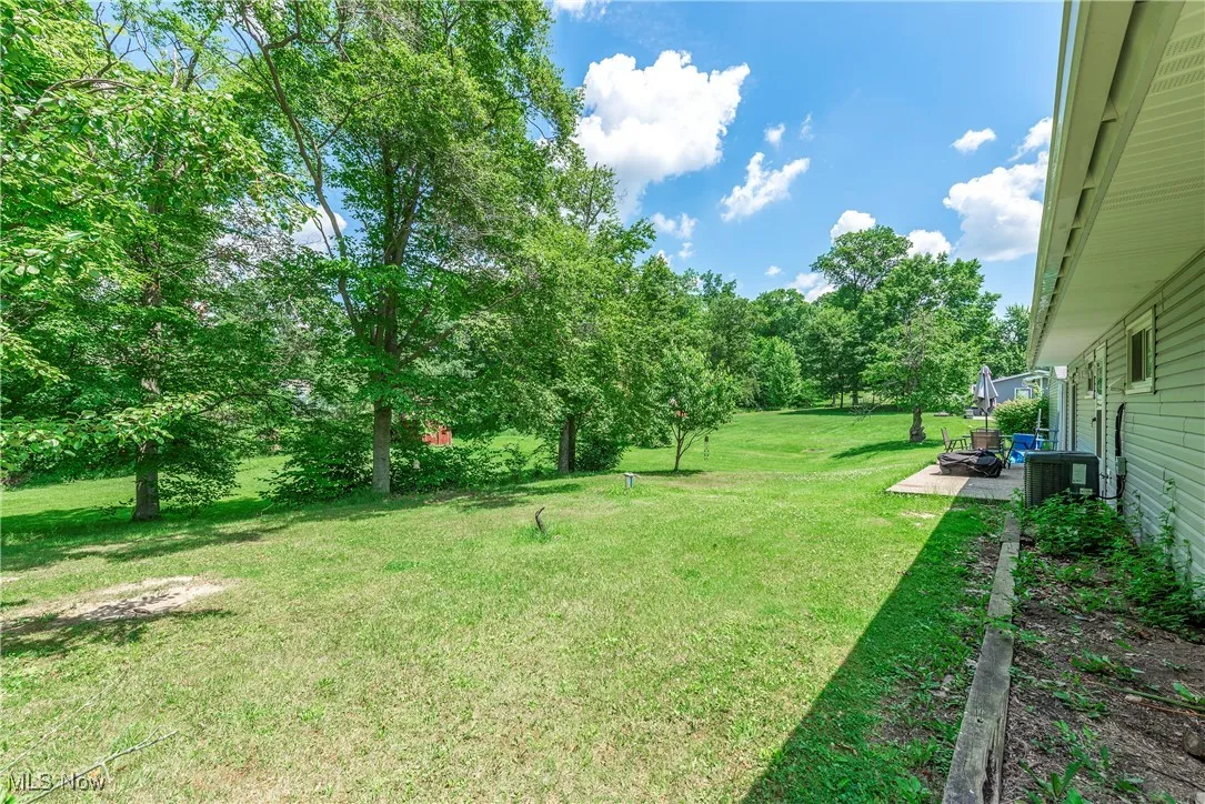 View of green lawn with a patio area