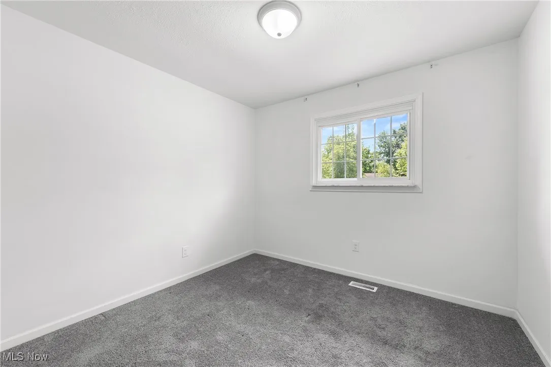 Spare room with dark carpet and baseboards