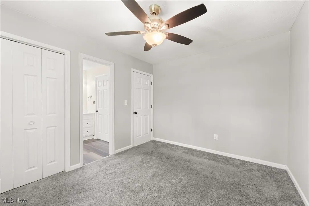 Unfurnished bedroom with carpet floors, a closet, ceiling fan, and ensuite bathroom