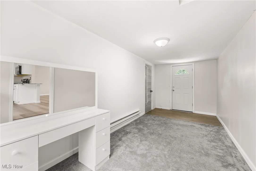Unfurnished office featuring a baseboard radiator and light colored carpet