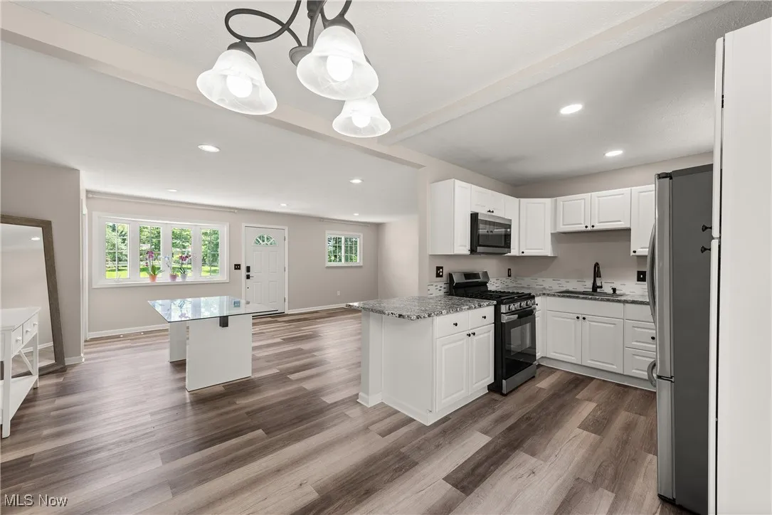 Kitchen featuring stainless steel appliances, plenty of natural light, dark wood-style floors, recessed lighting, and beamed ceiling