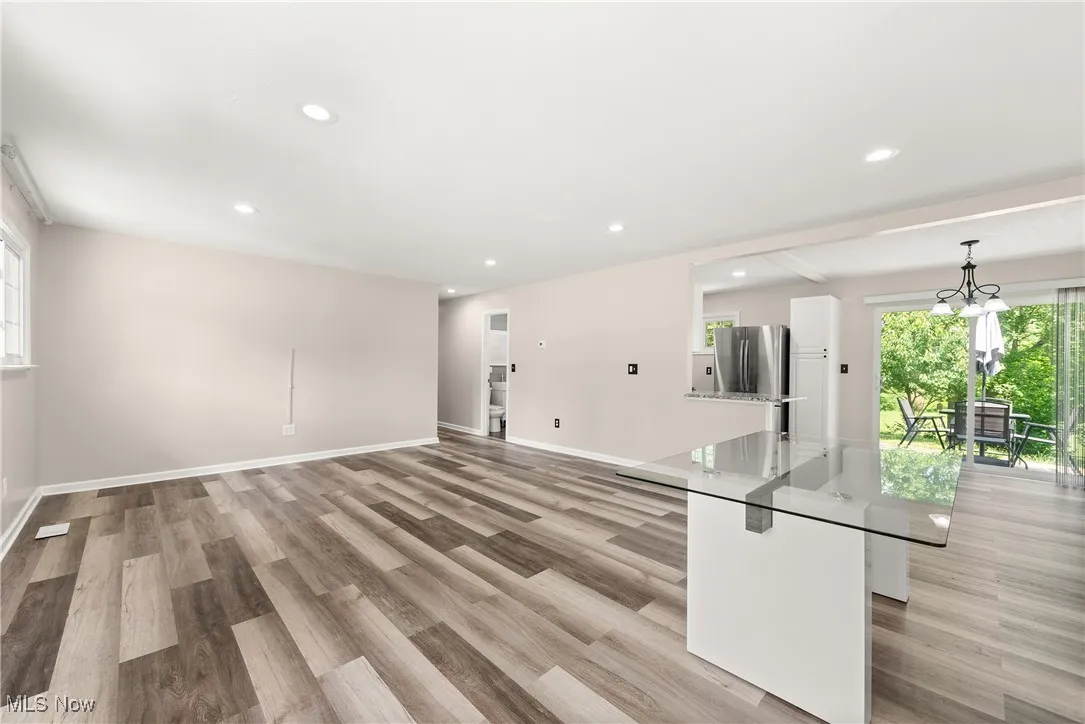 Unfurnished living room with light wood-style floors, recessed lighting, and a chandelier