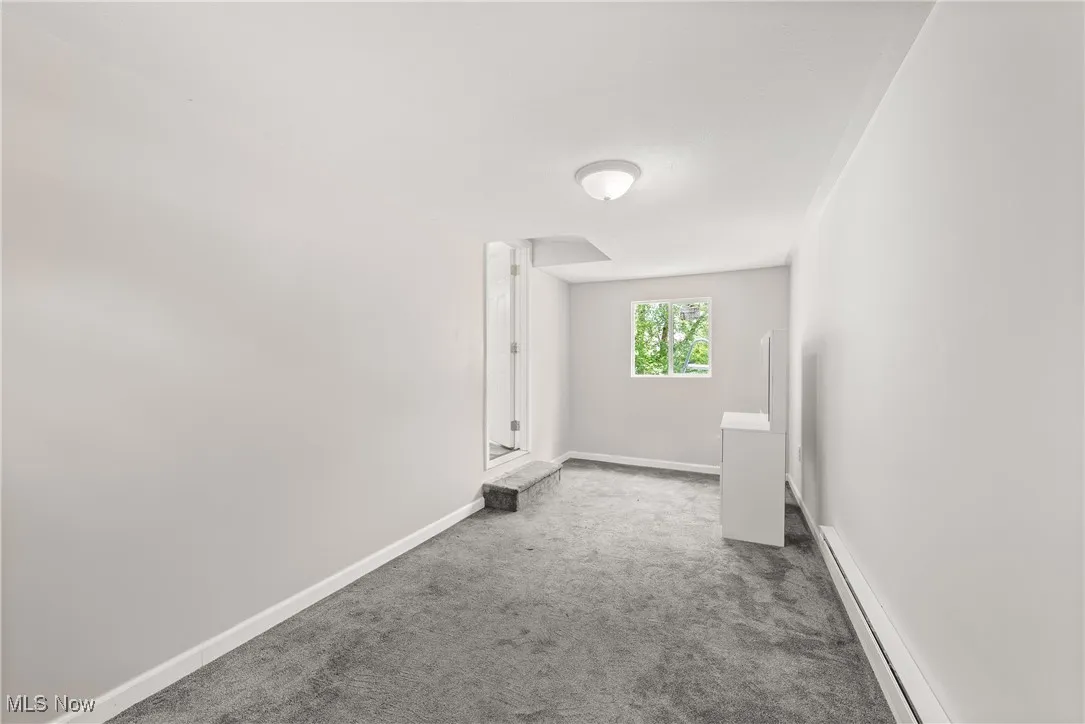 Carpeted spare room featuring baseboards and arched walkways