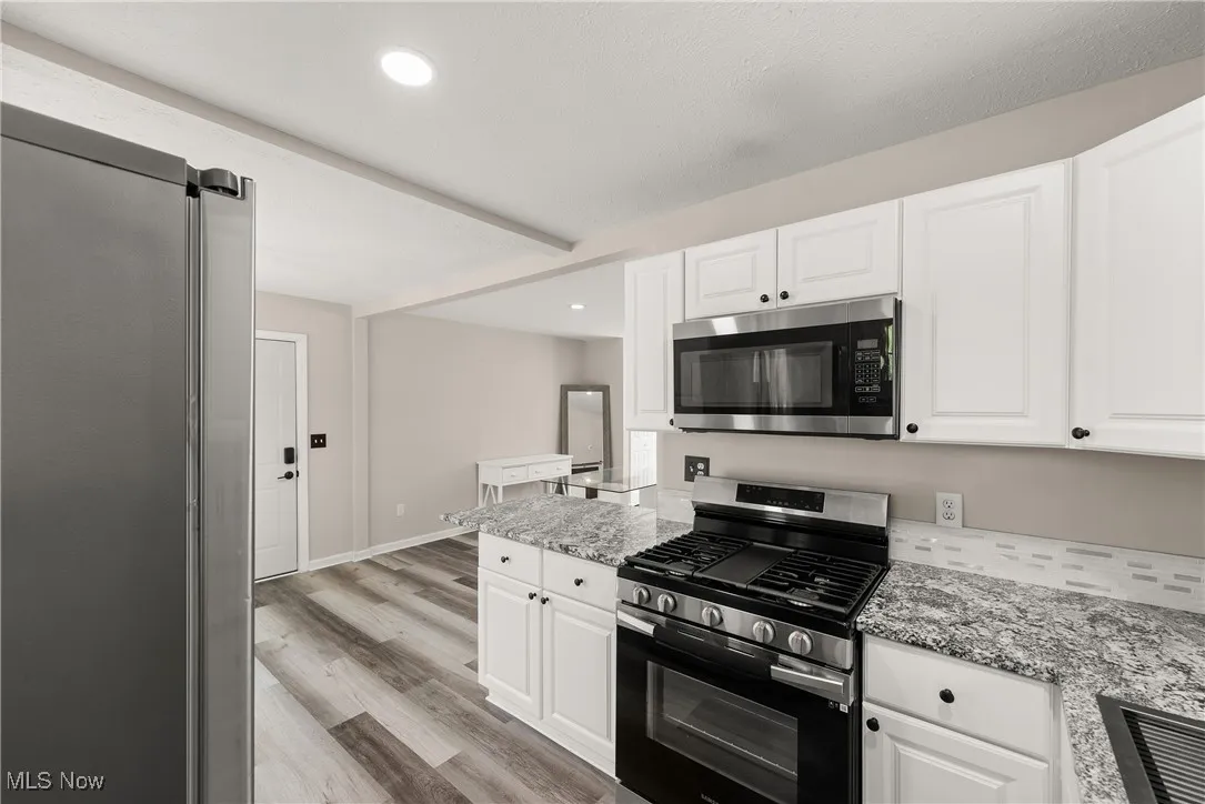 Kitchen with appliances with stainless steel finishes, light wood-style floors, white cabinetry, and recessed lighting