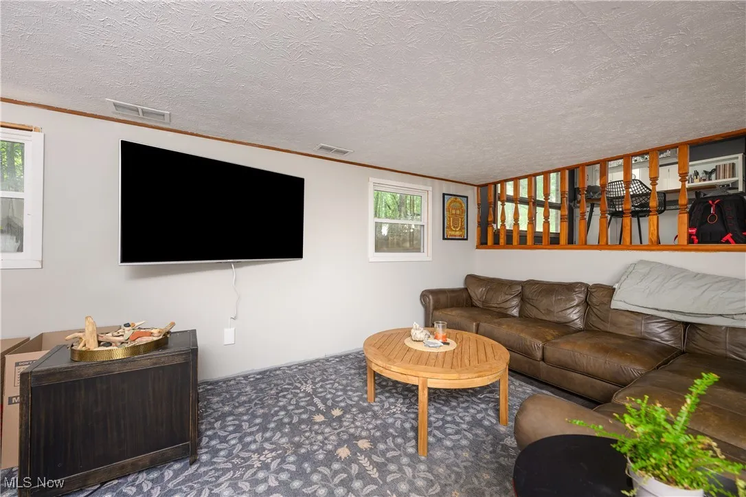 Carpeted living room with a textured ceiling and ornamental molding