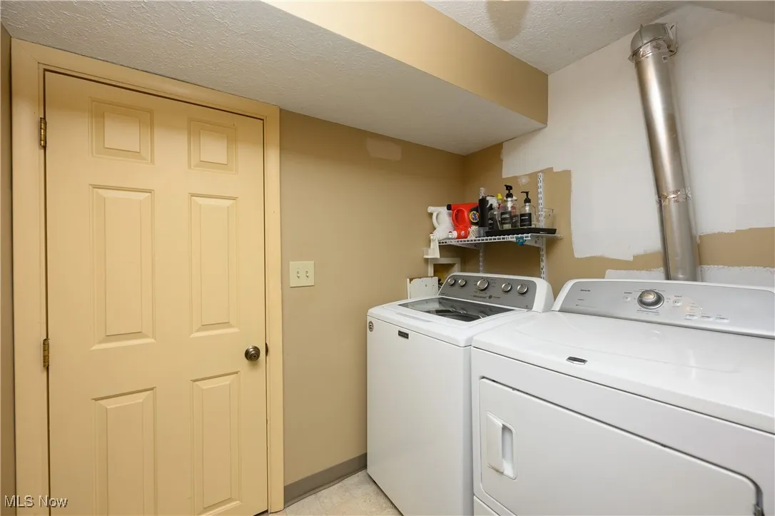 Laundry area featuring separate washer and dryer and a textured ceiling