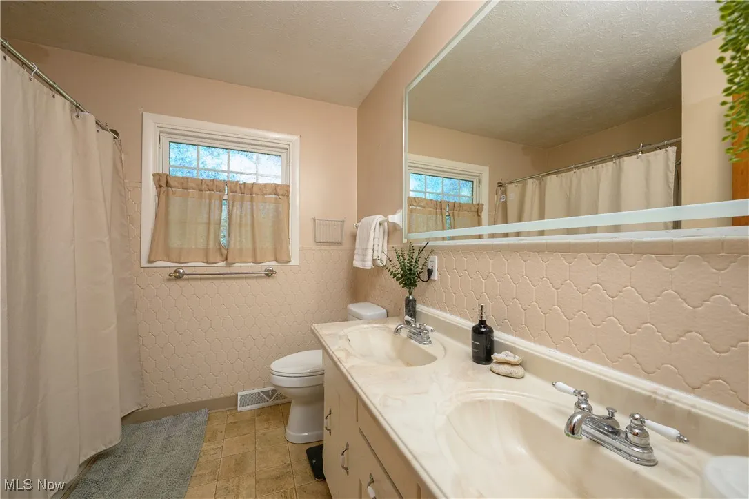 Full bathroom featuring double vanity and curtained shower