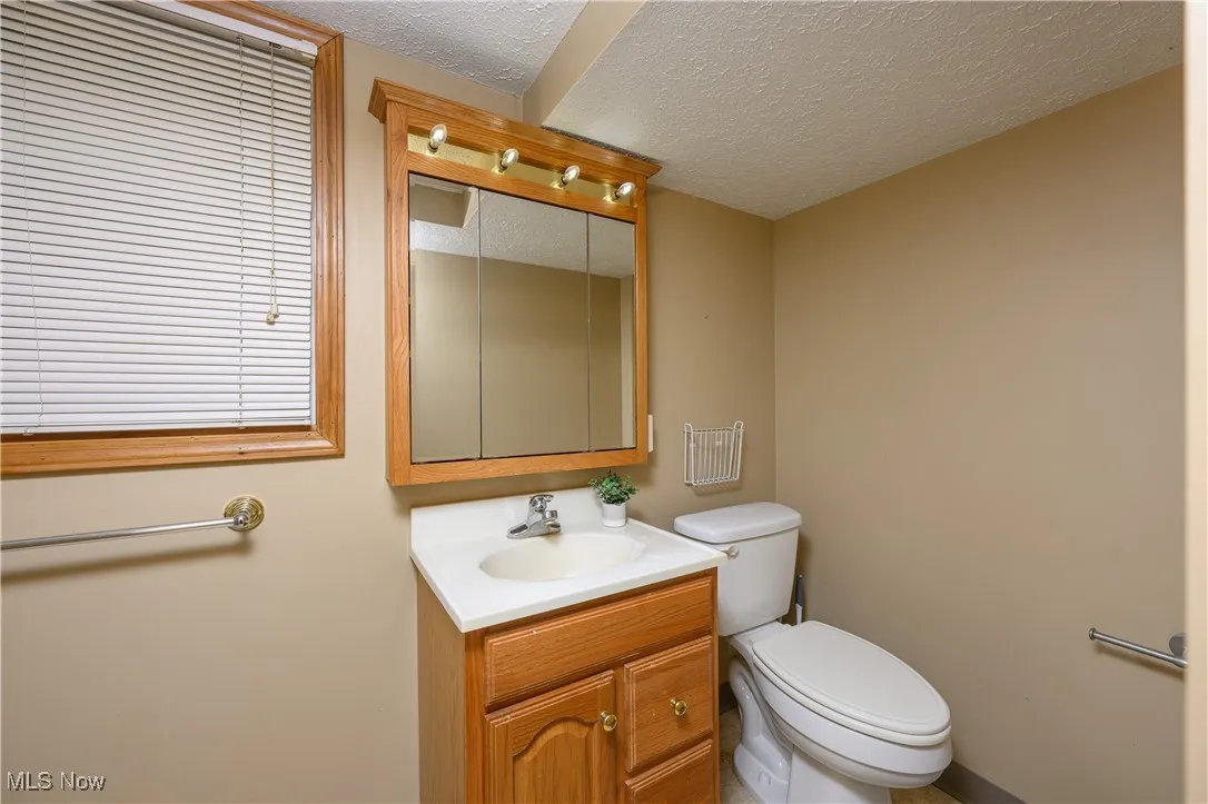 Half bathroom with a textured ceiling and vanity