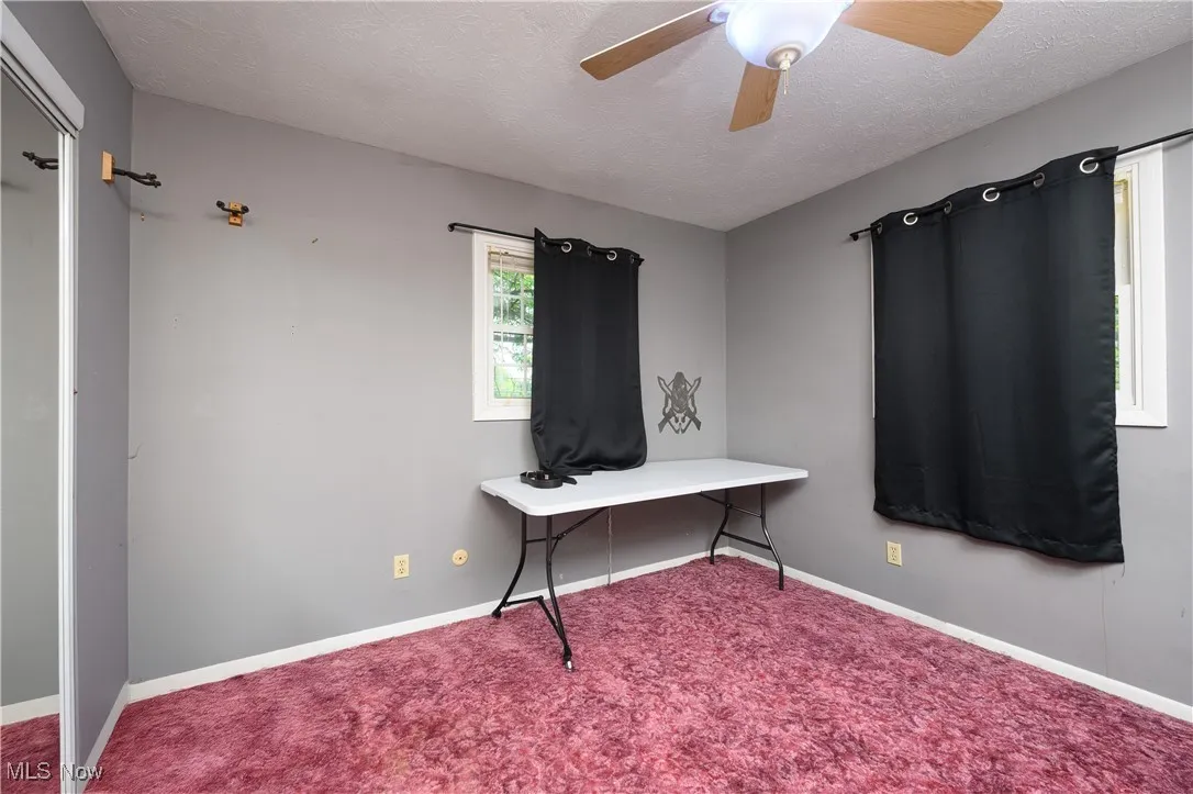 Office area featuring a textured ceiling, carpet flooring, and ceiling fan