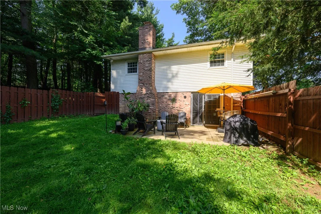 Back of property featuring a chimney, a patio area, a fenced backyard, and brick siding